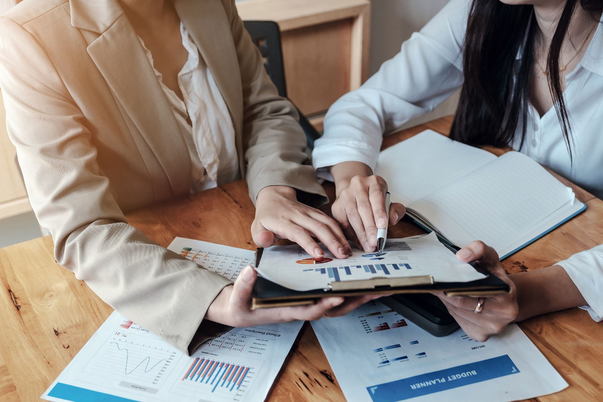 Two people sitting at a table looking at charts and graphs on a clipboard