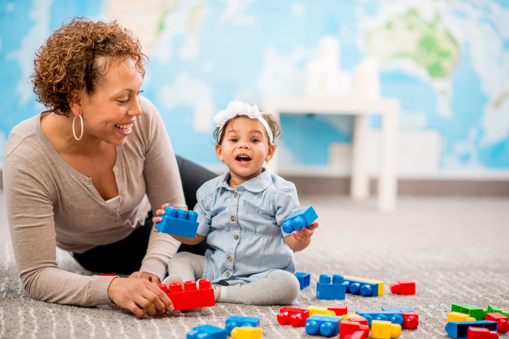 African American female sitting with a baby on the floor with blocks