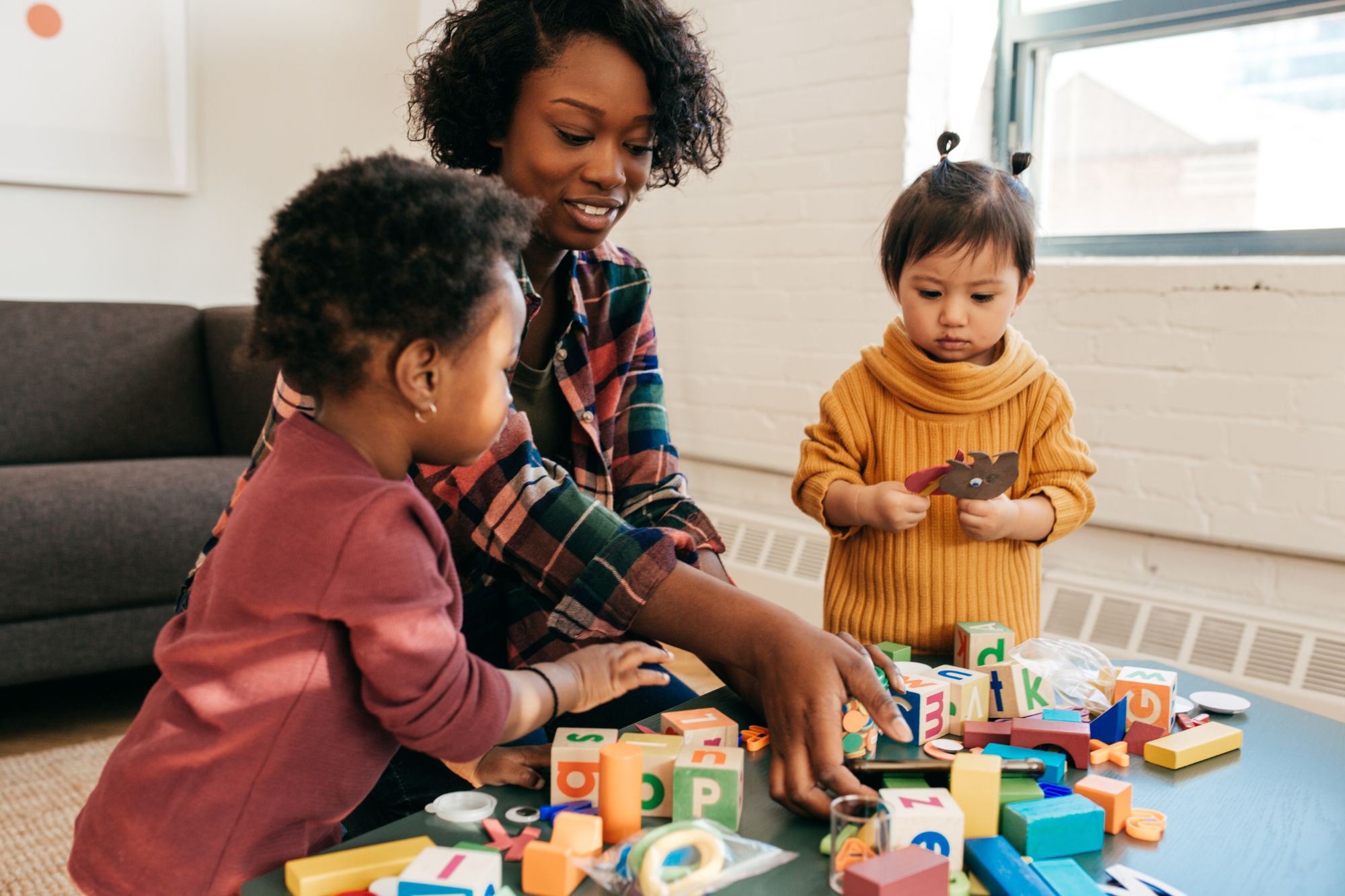 African American young woman playing two young children