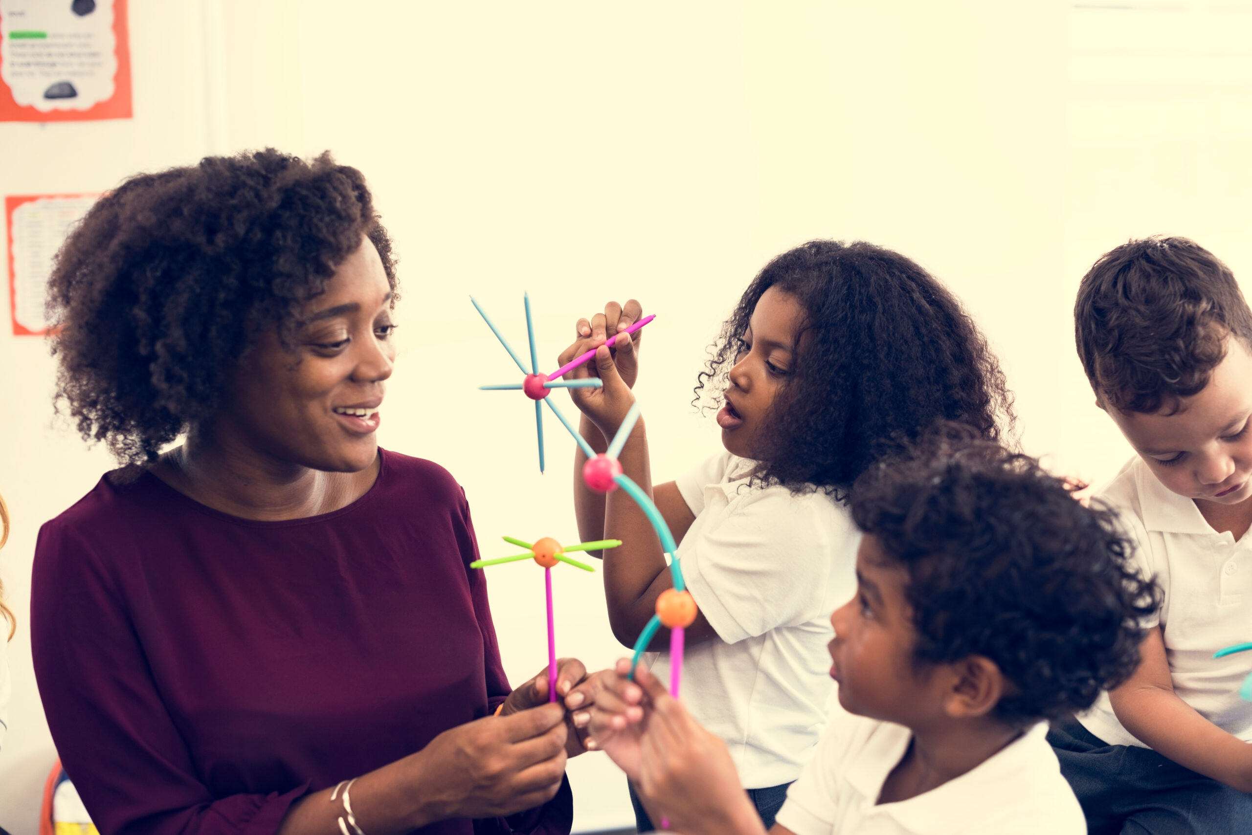 Teacher with two young students making projects with colorful sticks.