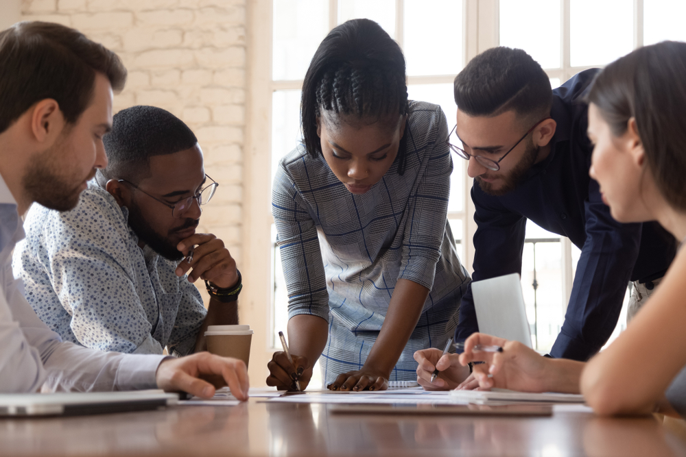 A diverse group of young professionals looking at documents around a table