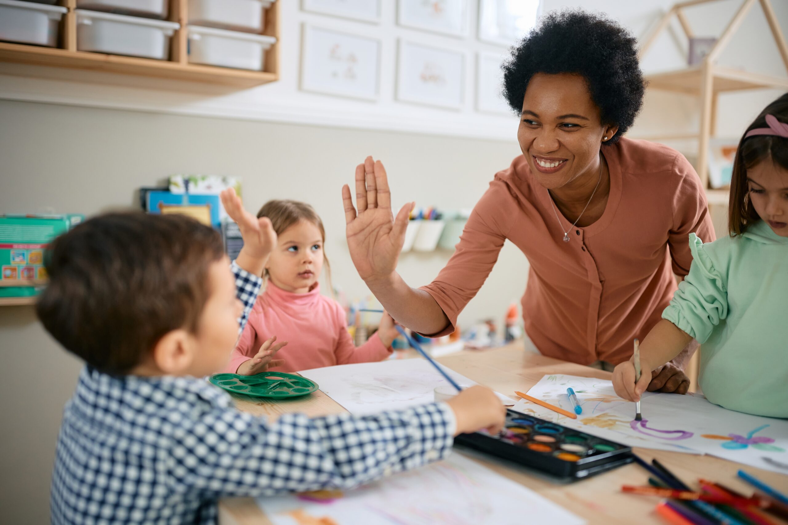 African American female teacher giving a high five to a young boy