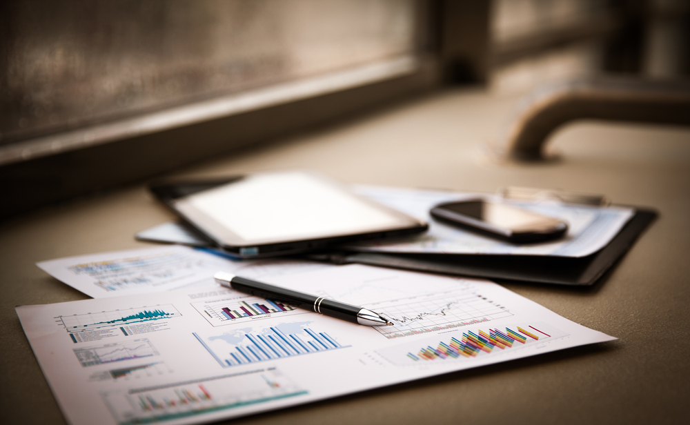 charts and graphs on paper on a table with a smartphone and pen