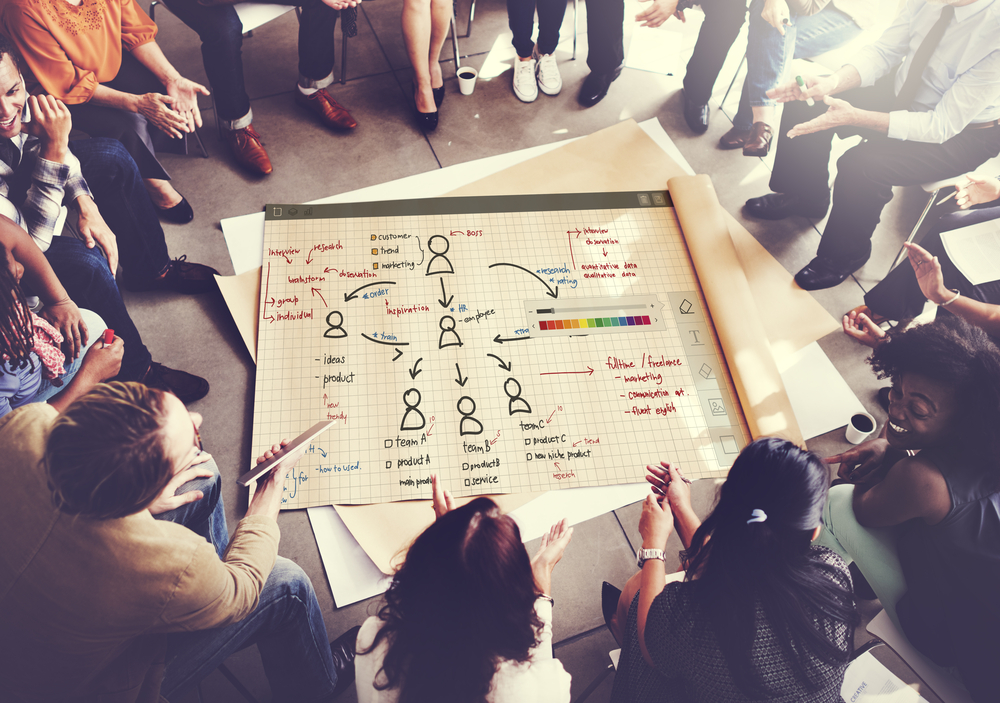 overhead view of people sitting in a circle looking at information on a paper chart