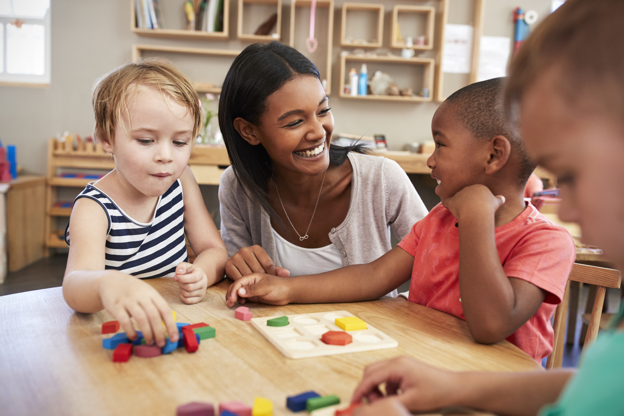 Woman smiling at a group of small children at a table
