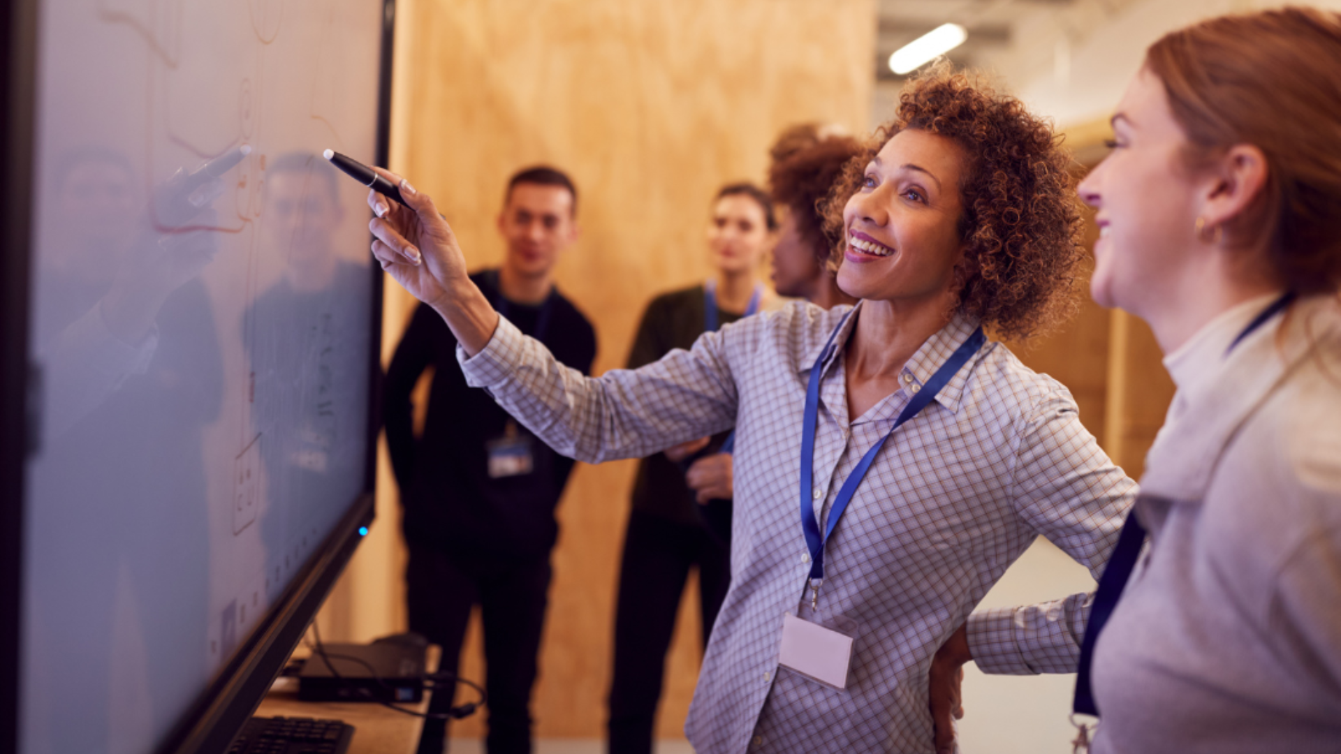 A woman points at a whiteboard while a group looks on.