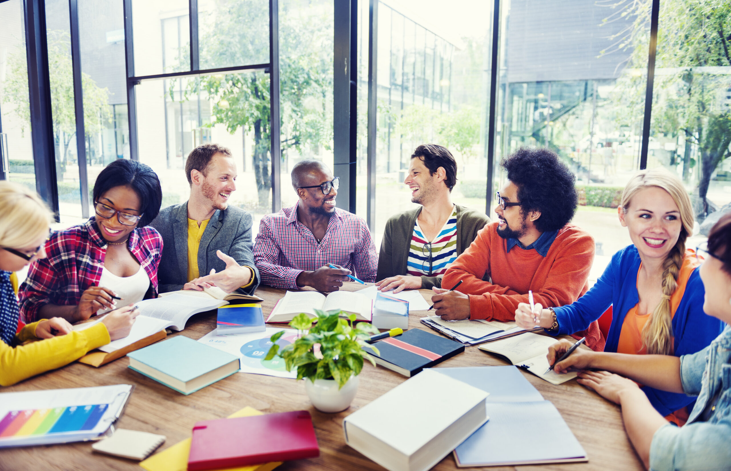 Group of professionals gathered around a table of books and reports