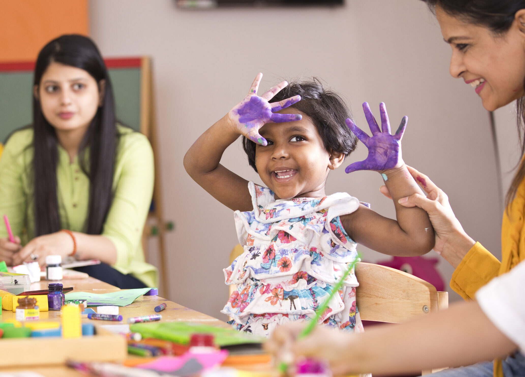 Teacher with preschool students having fun while finger painting at class