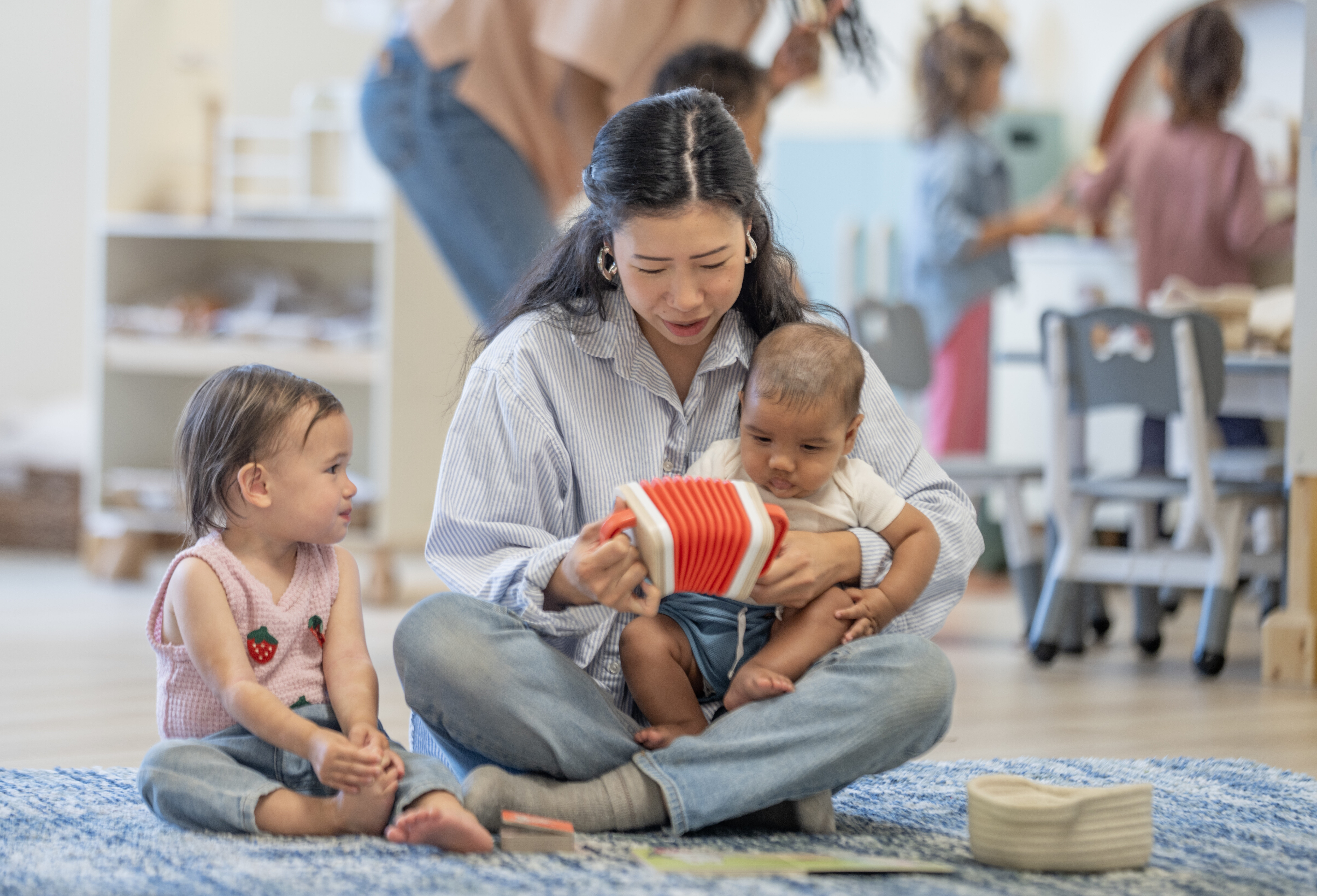 Woman with Two Children Reading in Cozy Playful Classroom Environment