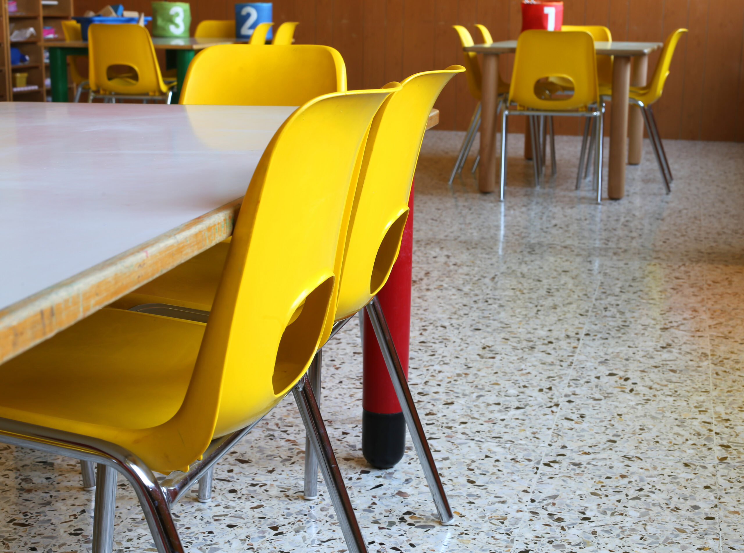 kindergarten classroom with tables and yellow chairs without children