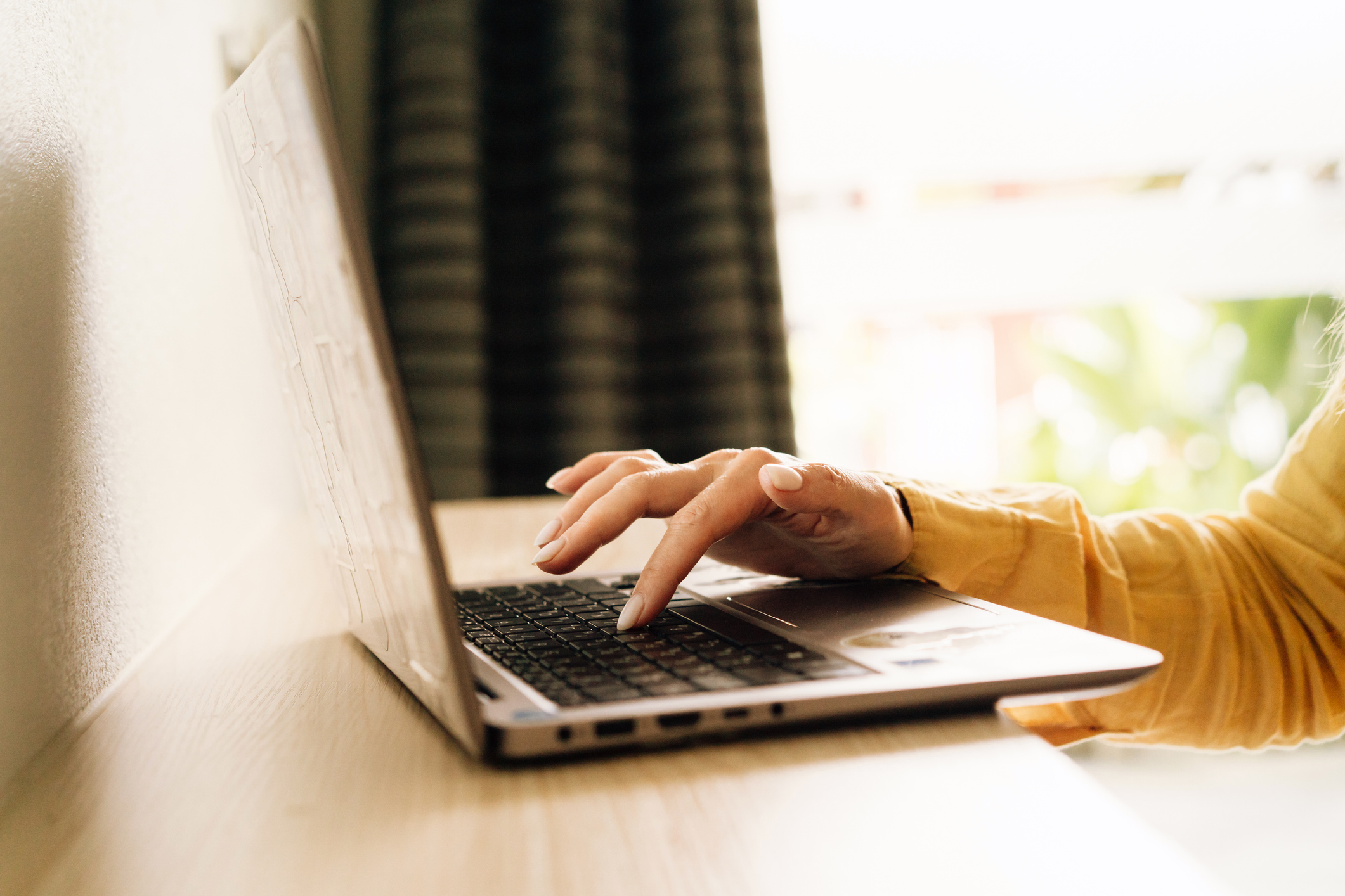 Closeup of a woman typing on a laptop keyboard alone