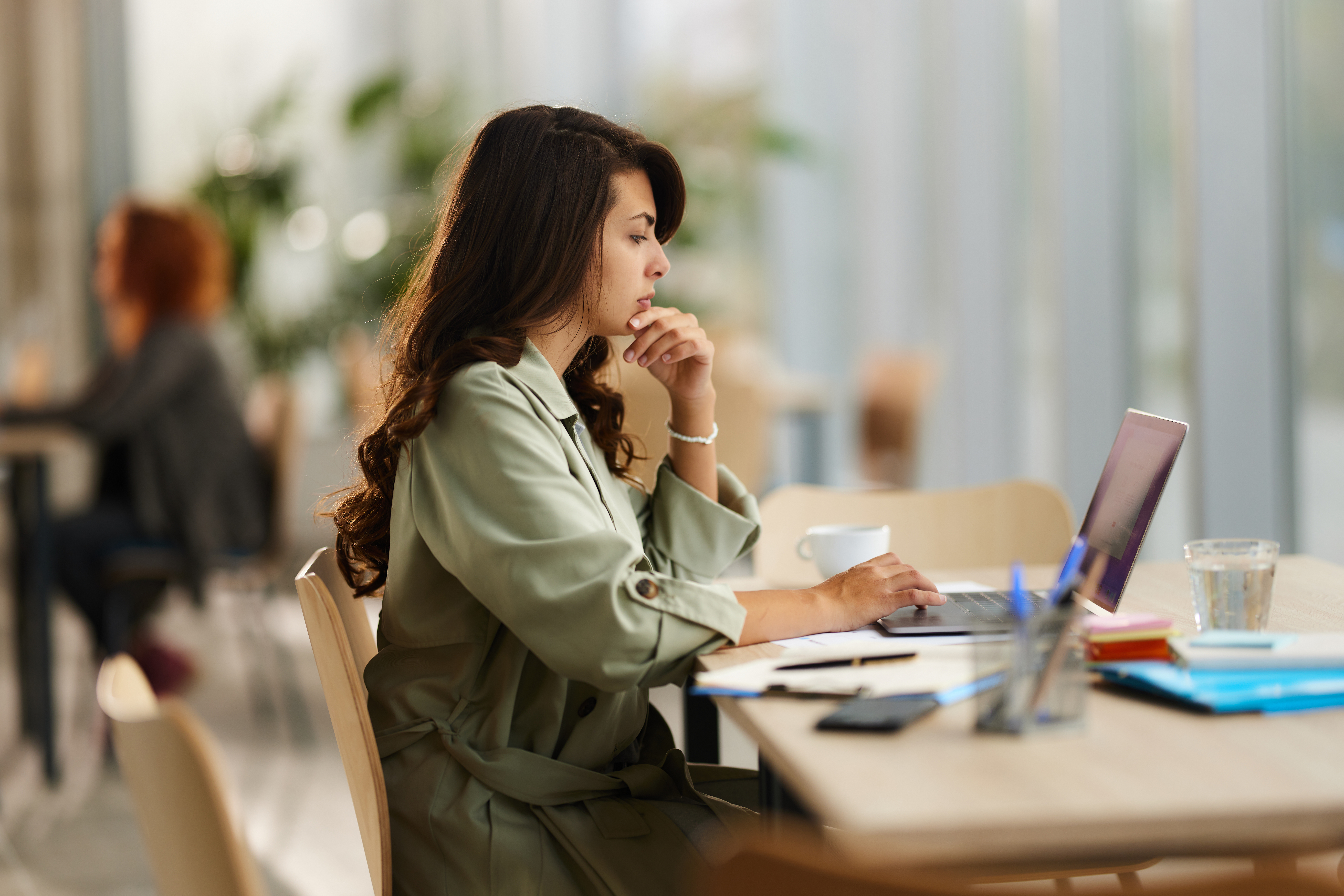Woman brainstorming while reading an e-mail on a computer in the office.